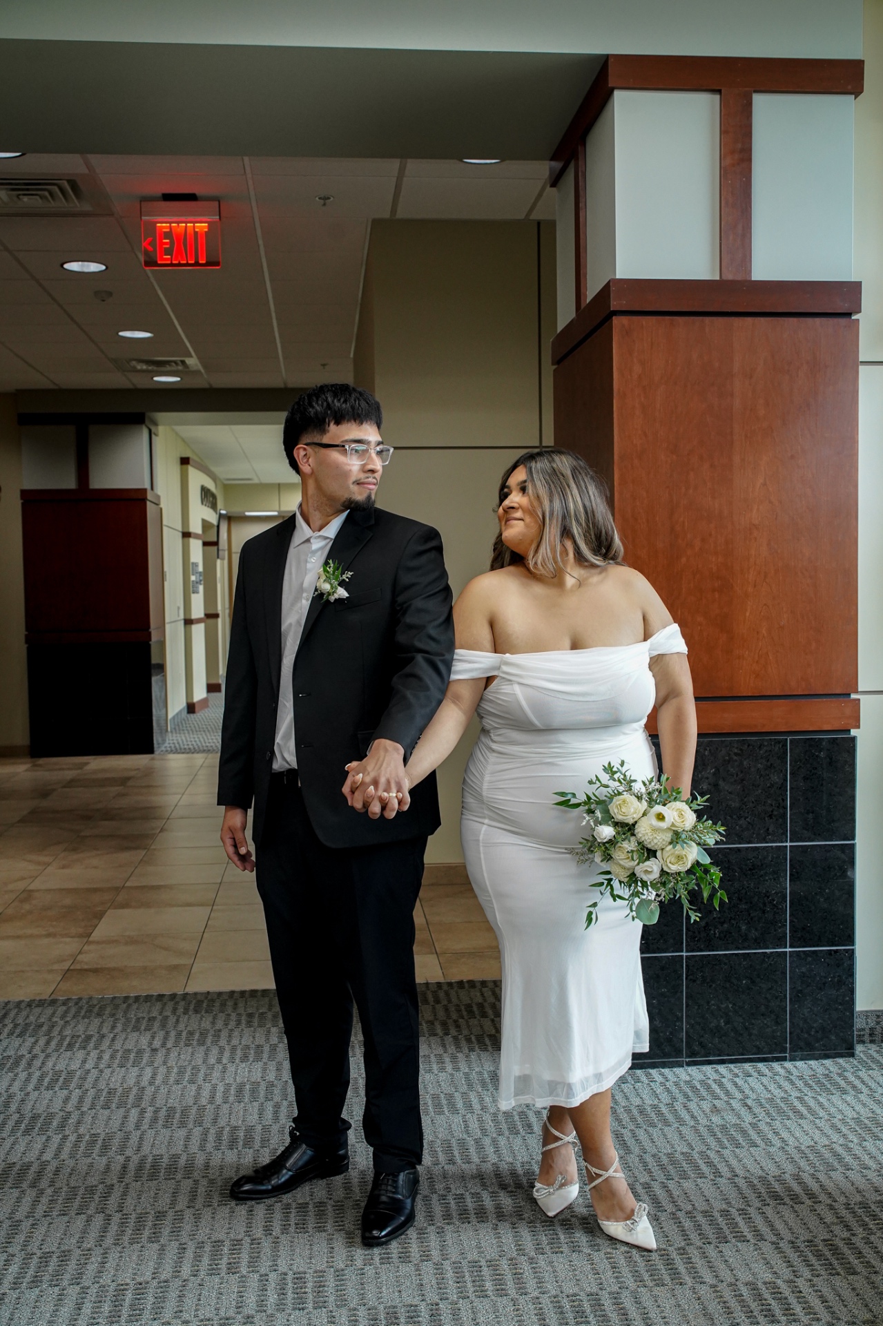 Bride and groom holding hands in the courthouse hallway